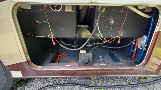 Open RV wet bay showing black and grey holding tanks and dump valves