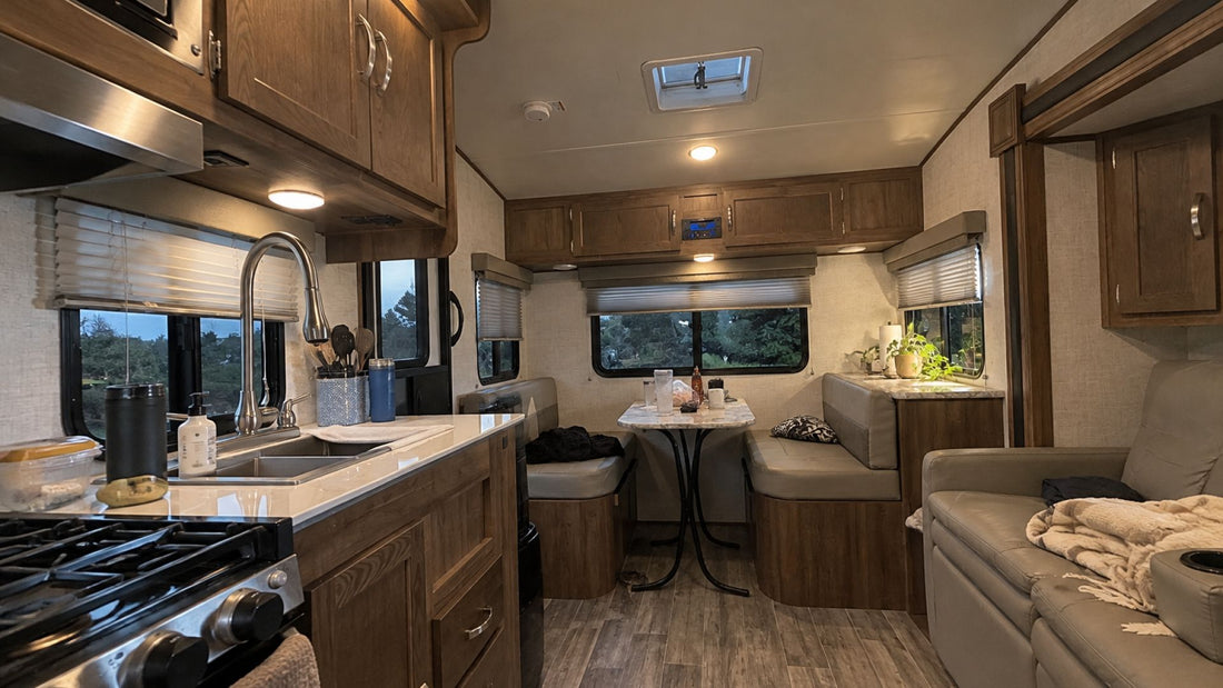 Modern RV kitchen and dinette with wood cabinets and cabin lighting